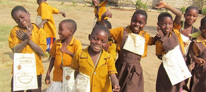 Children in Malawi with repurposed Vitameal bags used to carry school supplies